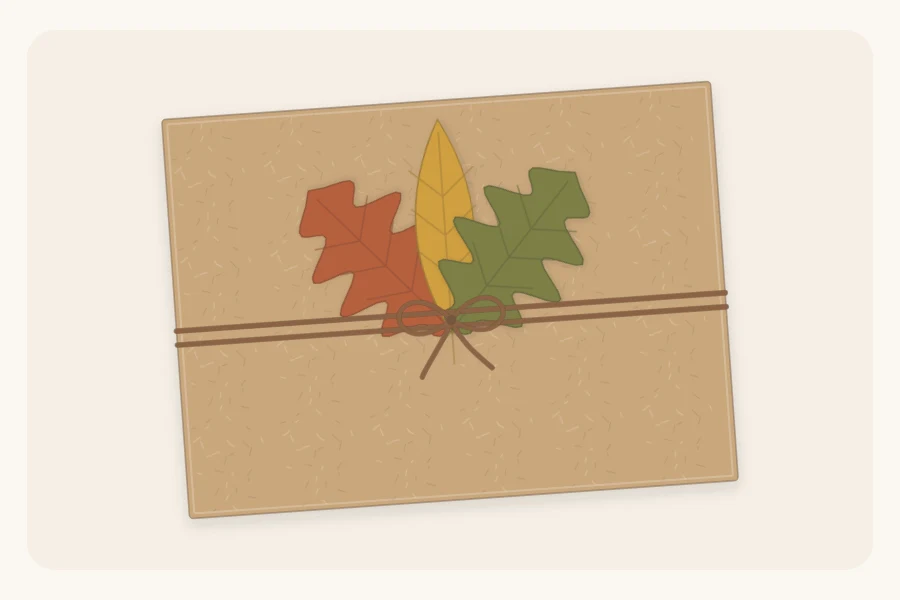 A kraft-wrapped box with three cut-paper leaves in rust, mustard and olive tucked under twine