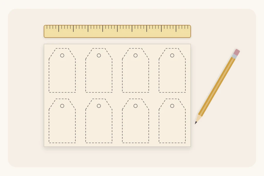 A sheet of cardstock marked into a grid of tag outlines beside a ruler and pencil