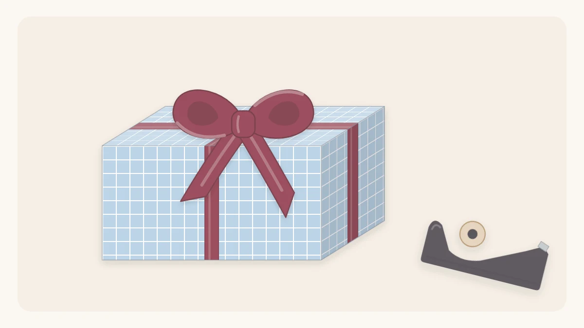 A wrapped box held closed by a ribbon tied in a cross with a bow, an empty tape dispenser beside it