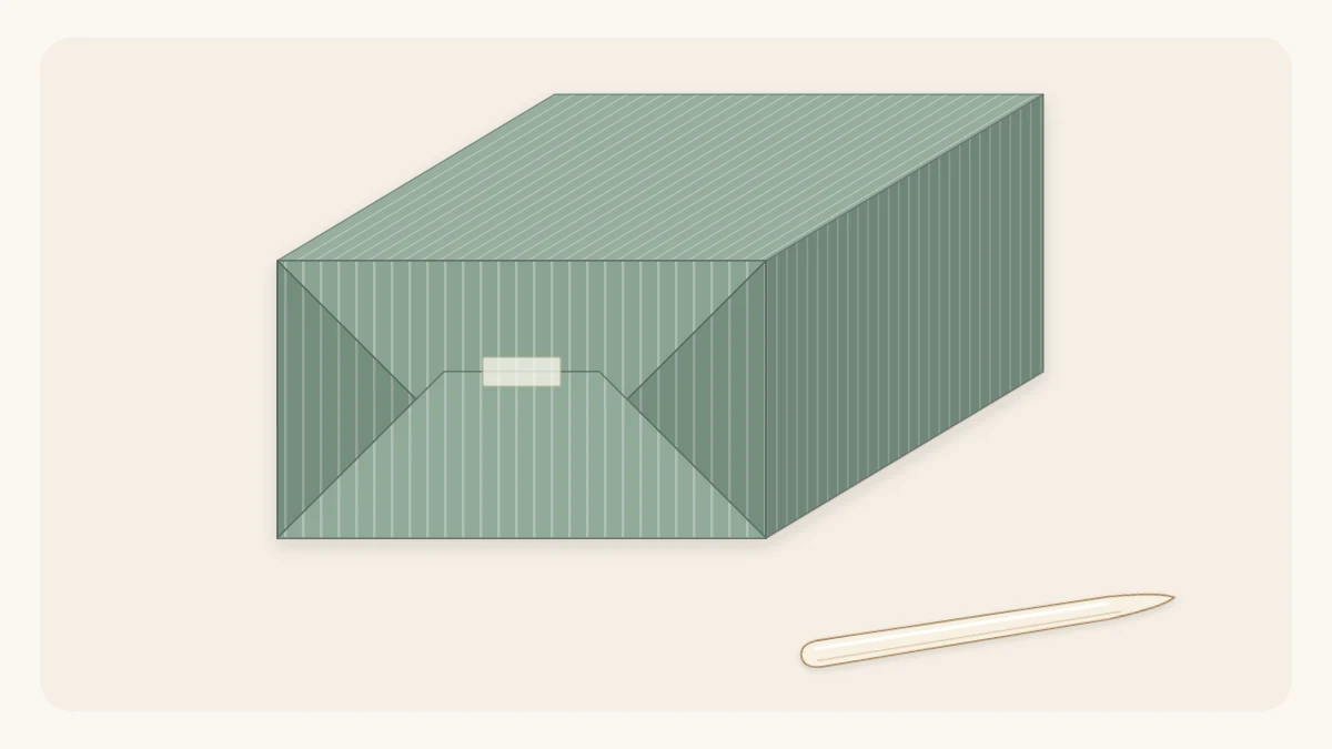 End of a wrapped gift box with crisp diagonal creases and a bone folder beside it