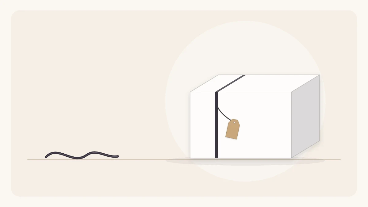 A gift in plain white paper with one thin off-center black ribbon and a small plain tag